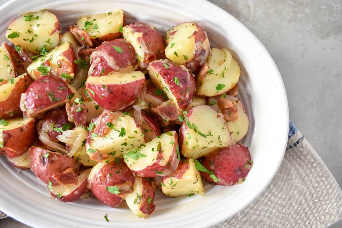 A close-up image of the potato salad served in a white bowl.