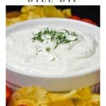 Dill dip served in a white bowl, garnished with chopped dill and surrounded by chips and grape tomatoes.