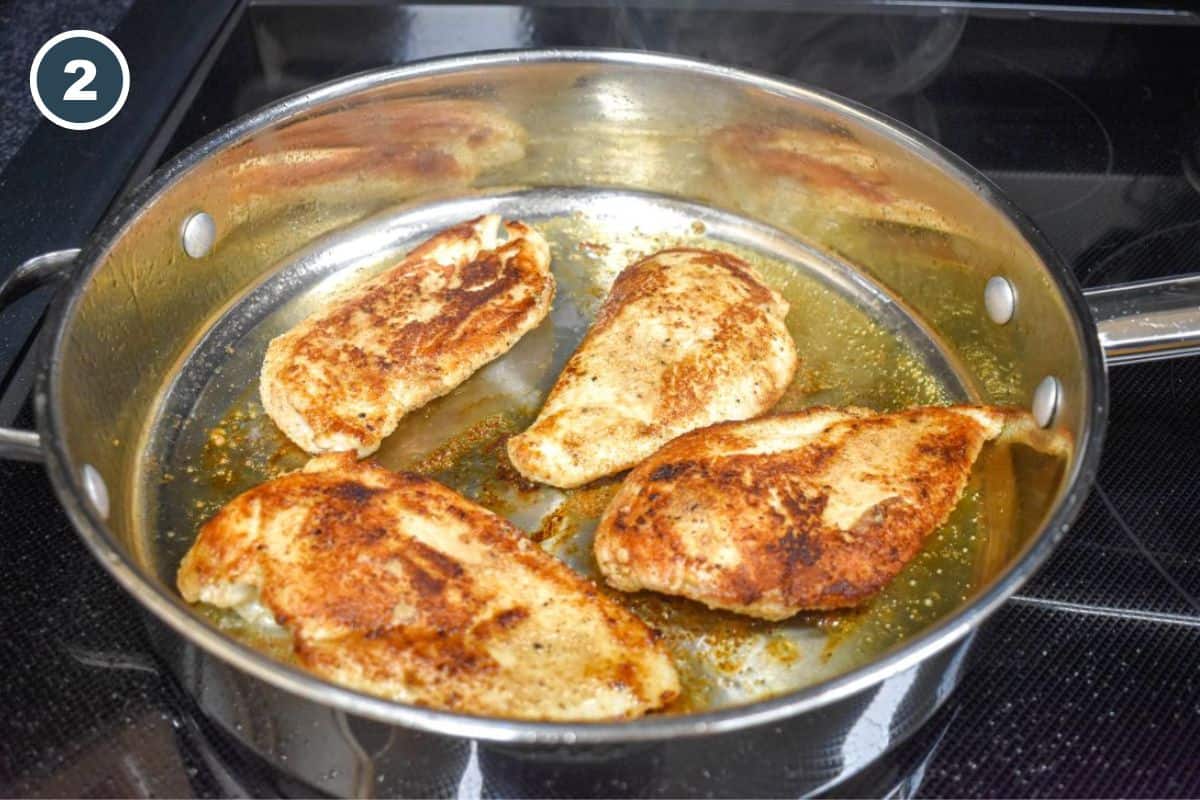 Chicken cutlets browned on both sides in a stainless steel skillet.