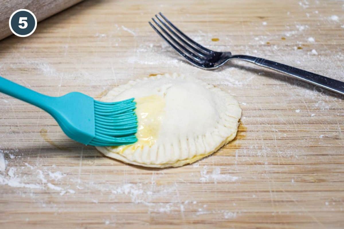 Brushing egg wash on the top of the sealed biscuit.