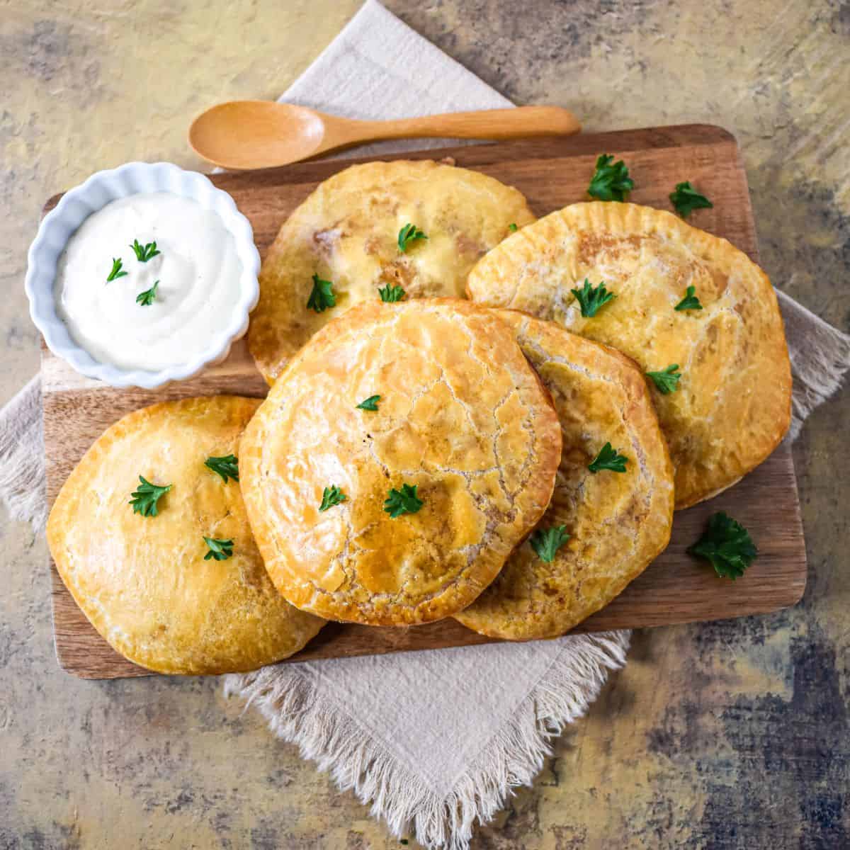 The stuffed biscuits on a wooden board with dipping sauce.