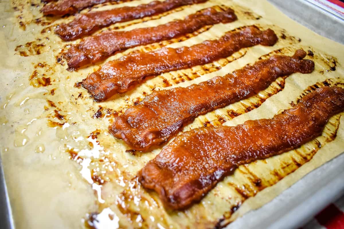 Cooked bacon on a baking sheet lined with brown parchment paper.