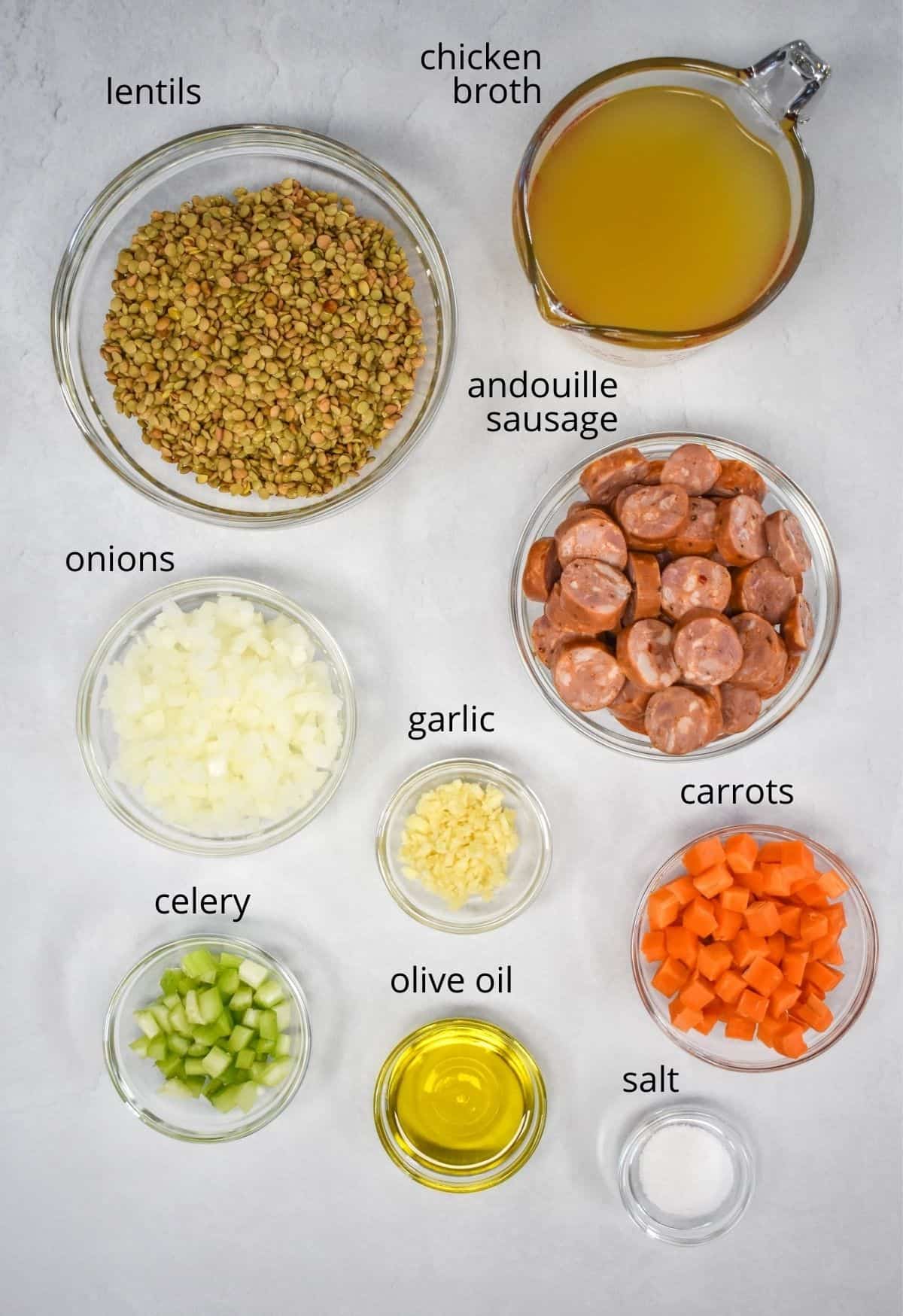 An image of the ingredients for the soup, prepped and arranged in glass bowls on a white table.