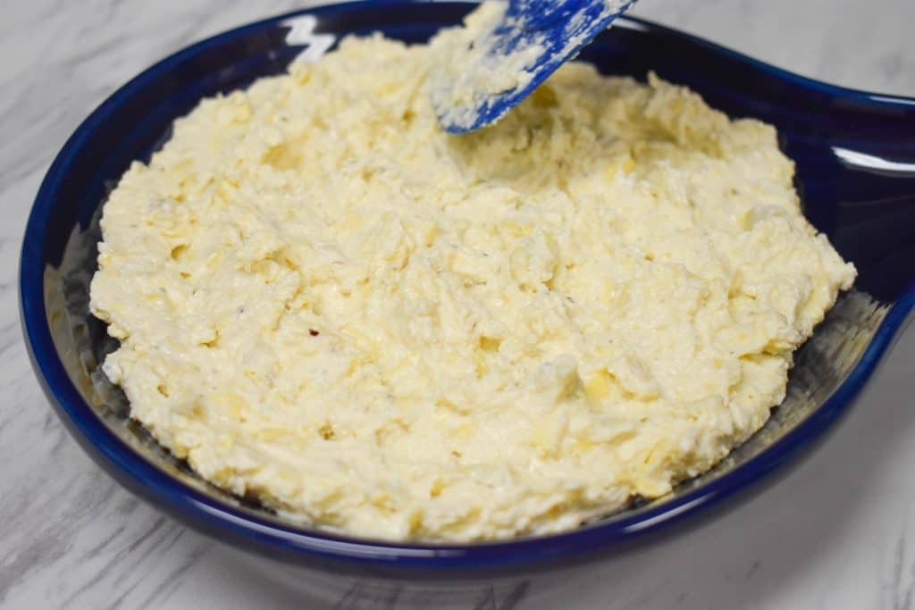 Adding and arranging the artichoke dip to a baking dish.