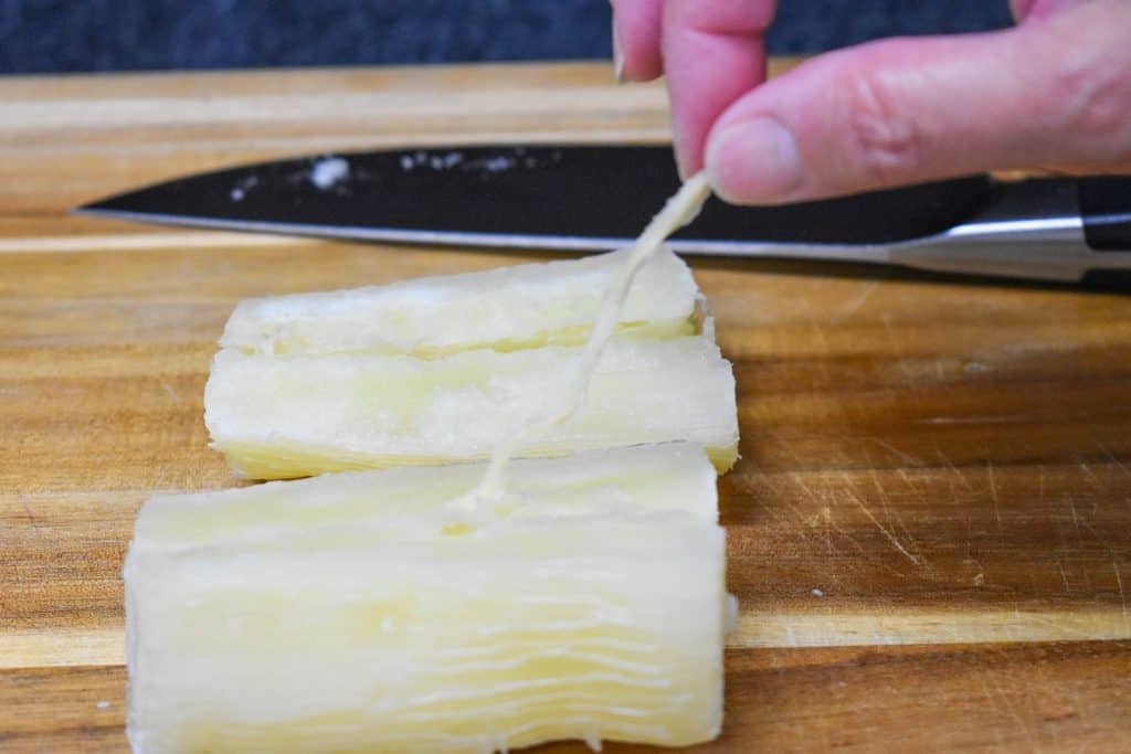 The stringy, woody piece in the inside of the yuca being removed.