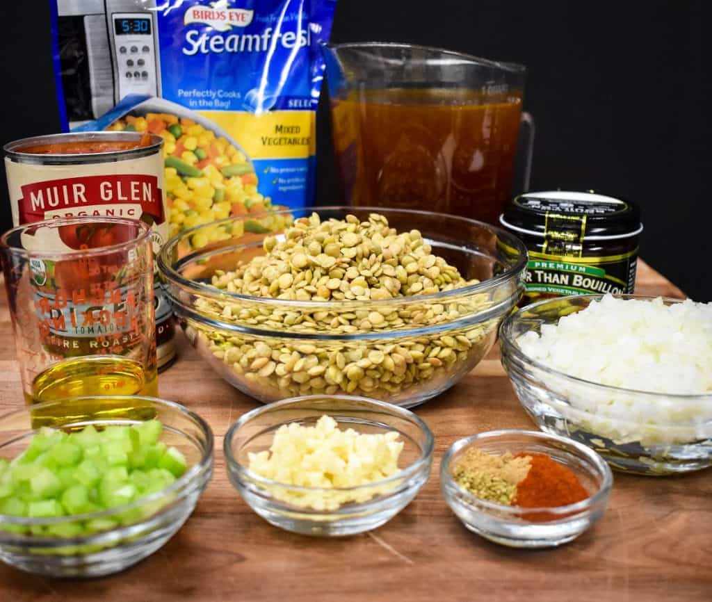 The ingredients for the lentil vegetable soup, before cooking, displayed on a wood cutting board.