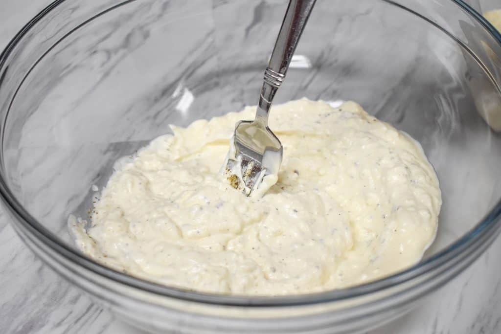 Cream cheese, mayonnaise and spices combined in a large, glass bowl.