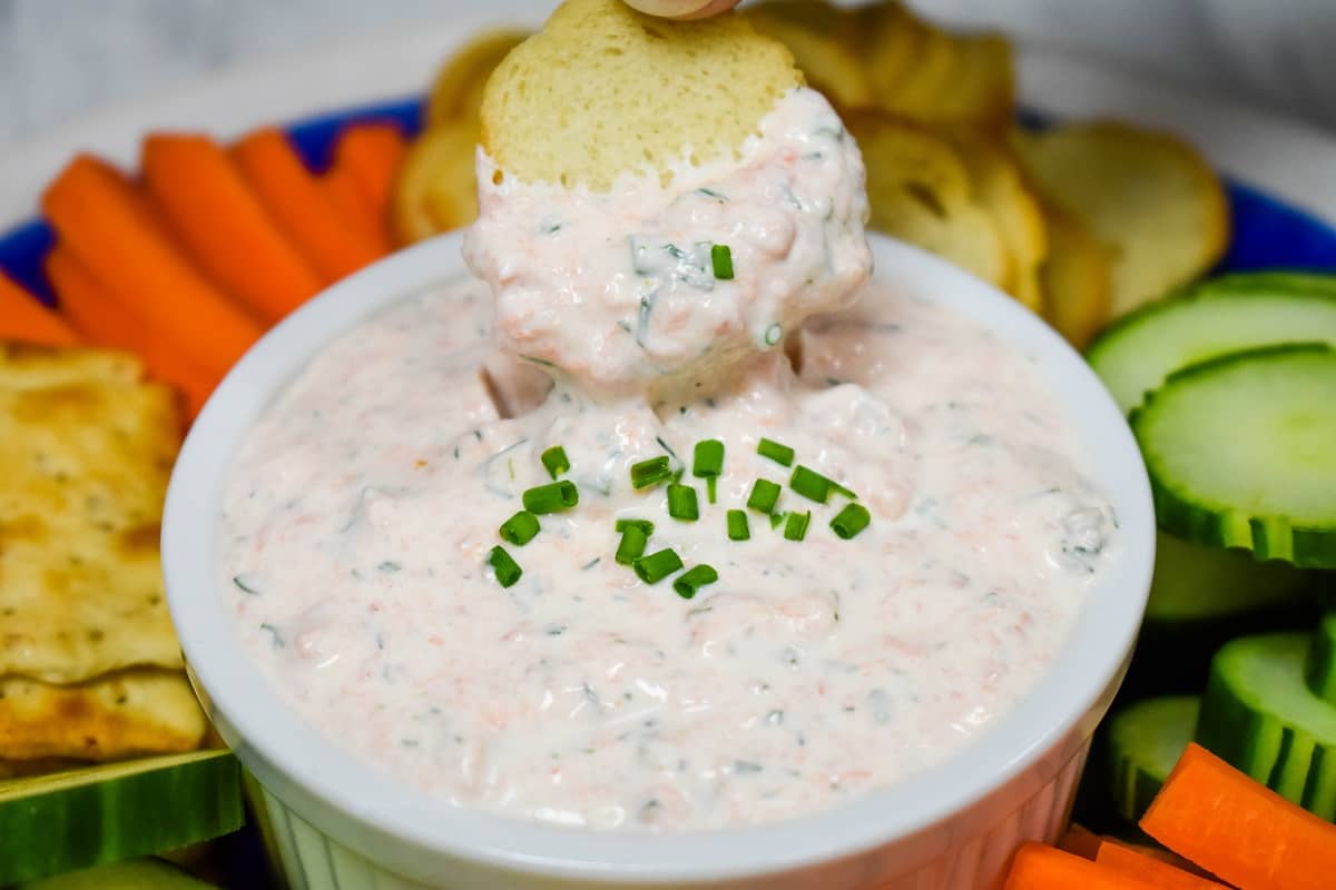 A close up picture of salmon dip being scooped by a bagel chip.