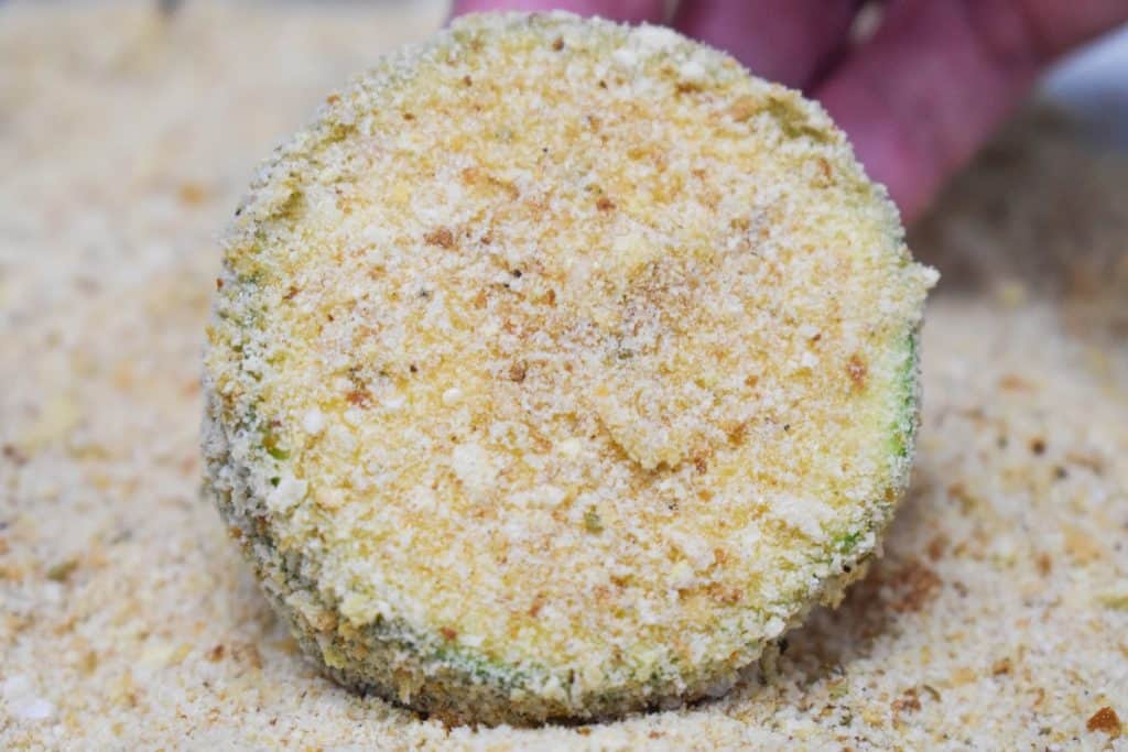 A close up picture of a zucchini round coated in breadcrumbs.