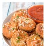 Fried zucchini rounds arranged on a white plate with a small bowl of marinara sauce.