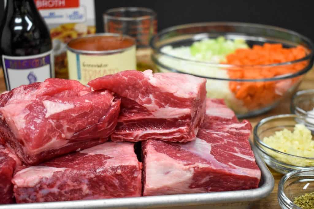 The ingredients for the short ribs recipe displayed on a wood cutting board.