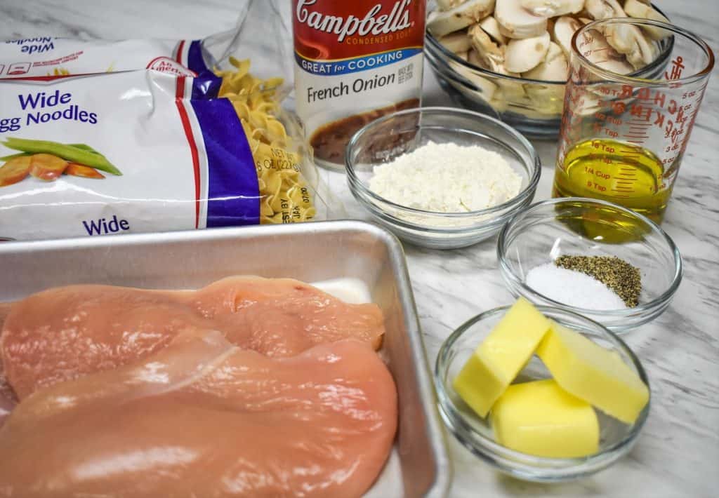 The ingredients for the chicken and noodles recipe displayed on a white table.