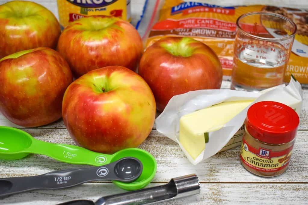 The ingredients for the cinnamon apples displayed on a white wood tables.