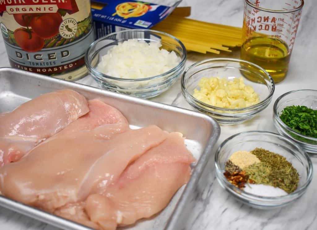 The ingredients for the linguine with chicken and tomatoes recipe displayed on a white table.