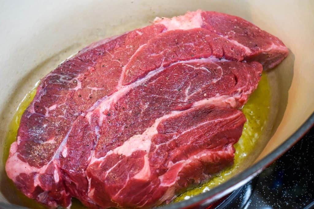 A large chuck pot roast in a large enameled cast iron pot.