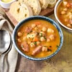 Bowl of Cuban-style chickpea soup served with sliced bread on the side.