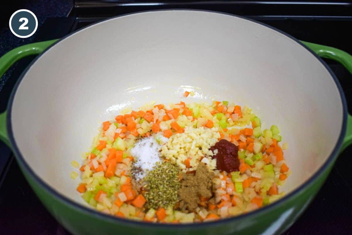Garlic, tomato paste, and spices added to the sautéed vegetables in the pot.