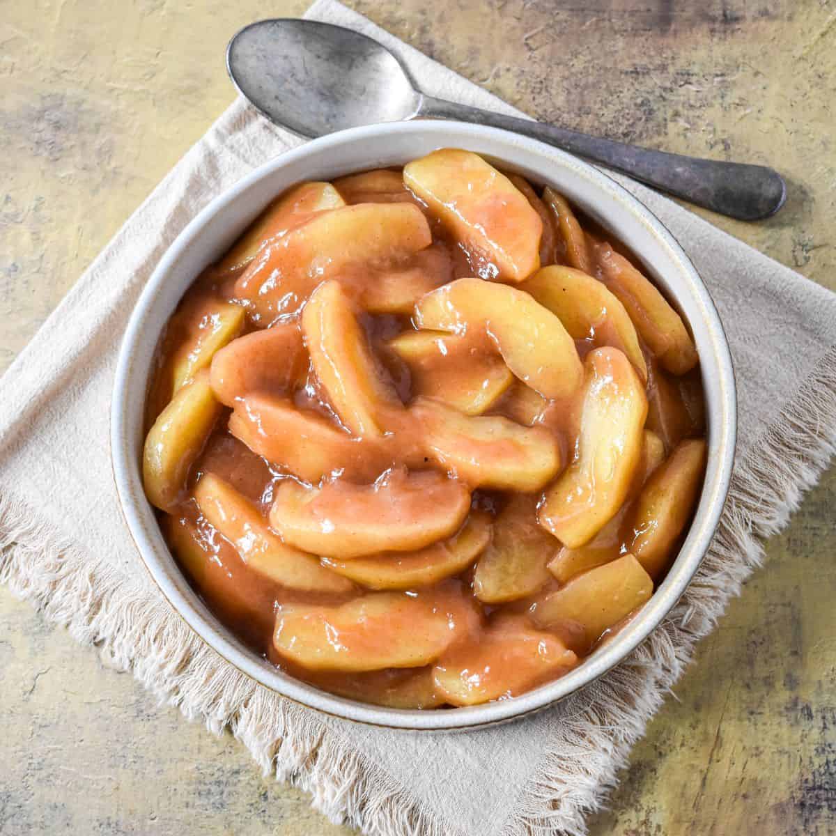 Bowl of cinnamon apples with tender slices in a warm, caramel-like sauce, ready to serve.