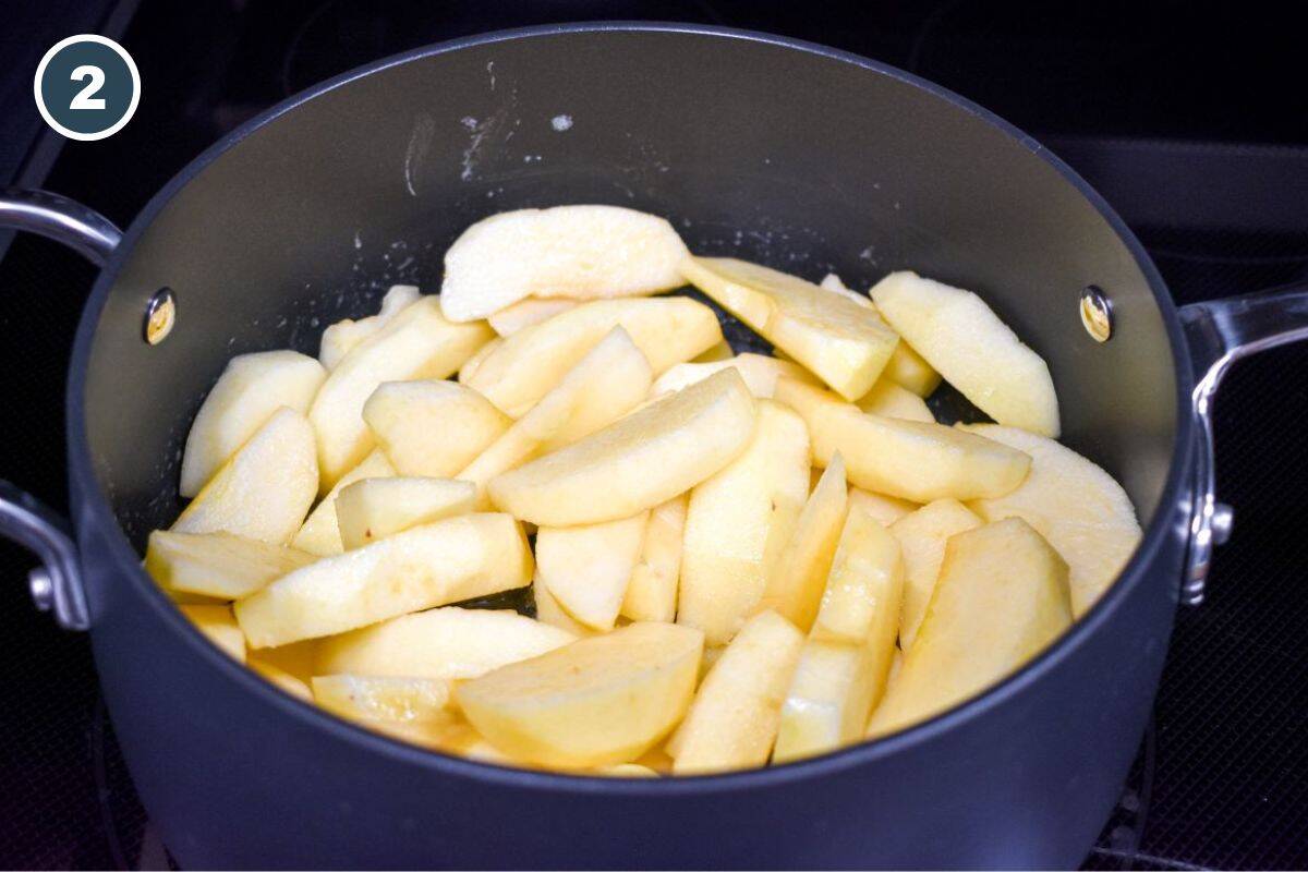 Sliced apples added to the saucepan with melted butter, starting to cook over medium heat.