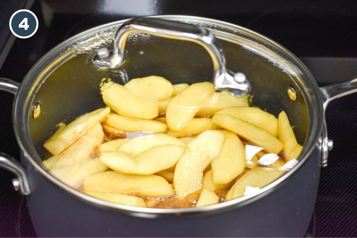 Sliced apples cooking in a saucepan with brown sugar and cinnamon, covered with a glass lid.