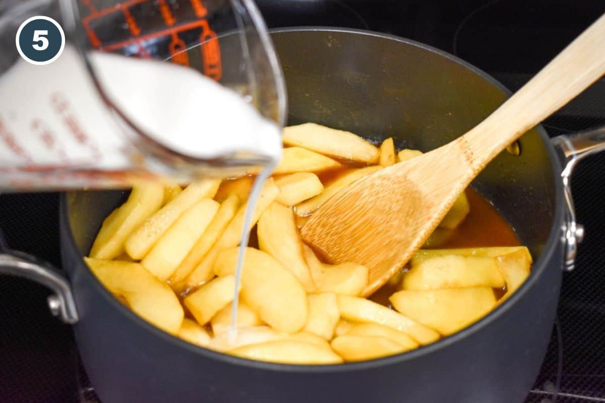 Cornstarch and water mixture being poured into a saucepan of simmering apples to thicken the sauce.