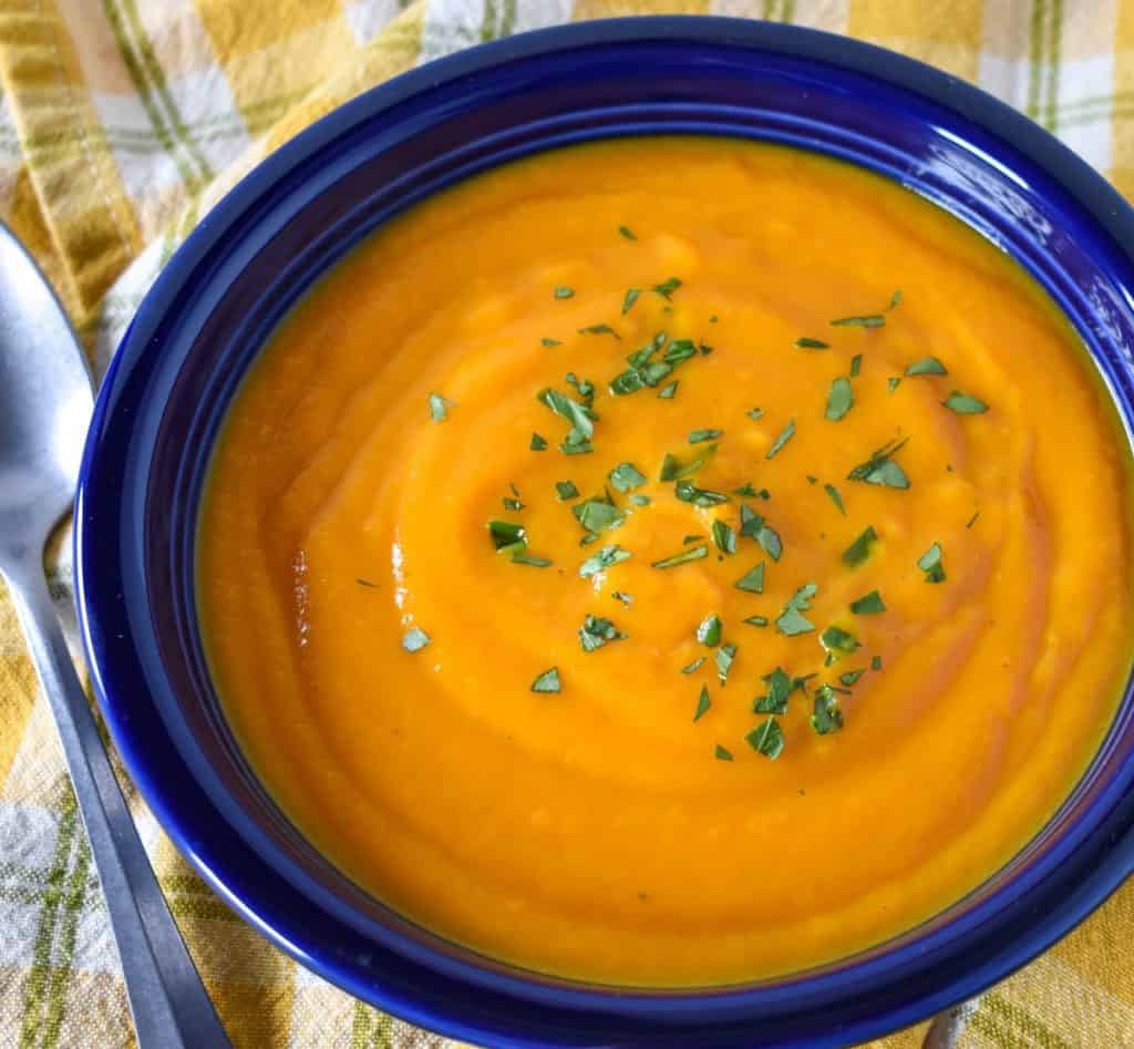 Carrot ginger soup served in a blue bowl.