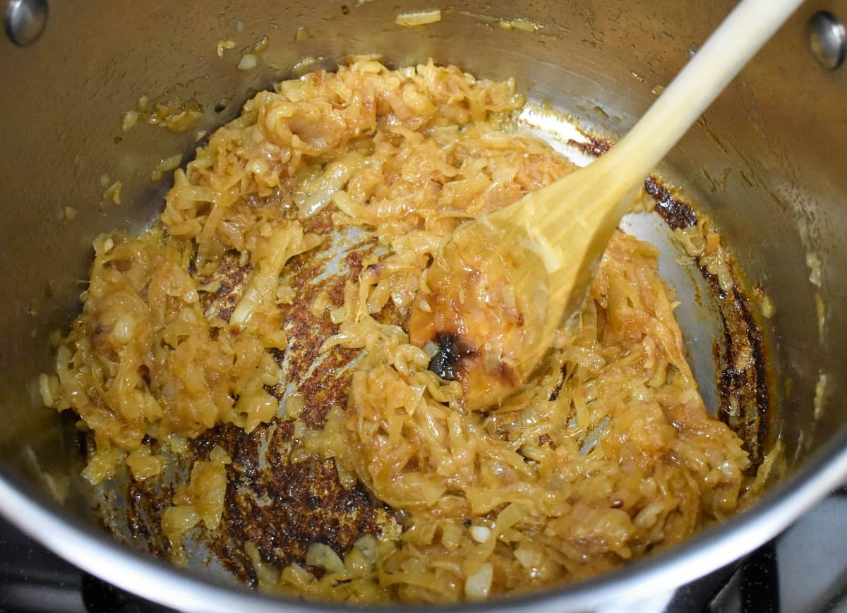 An image of the caramelized onions in a large pot with a wooden spoon.