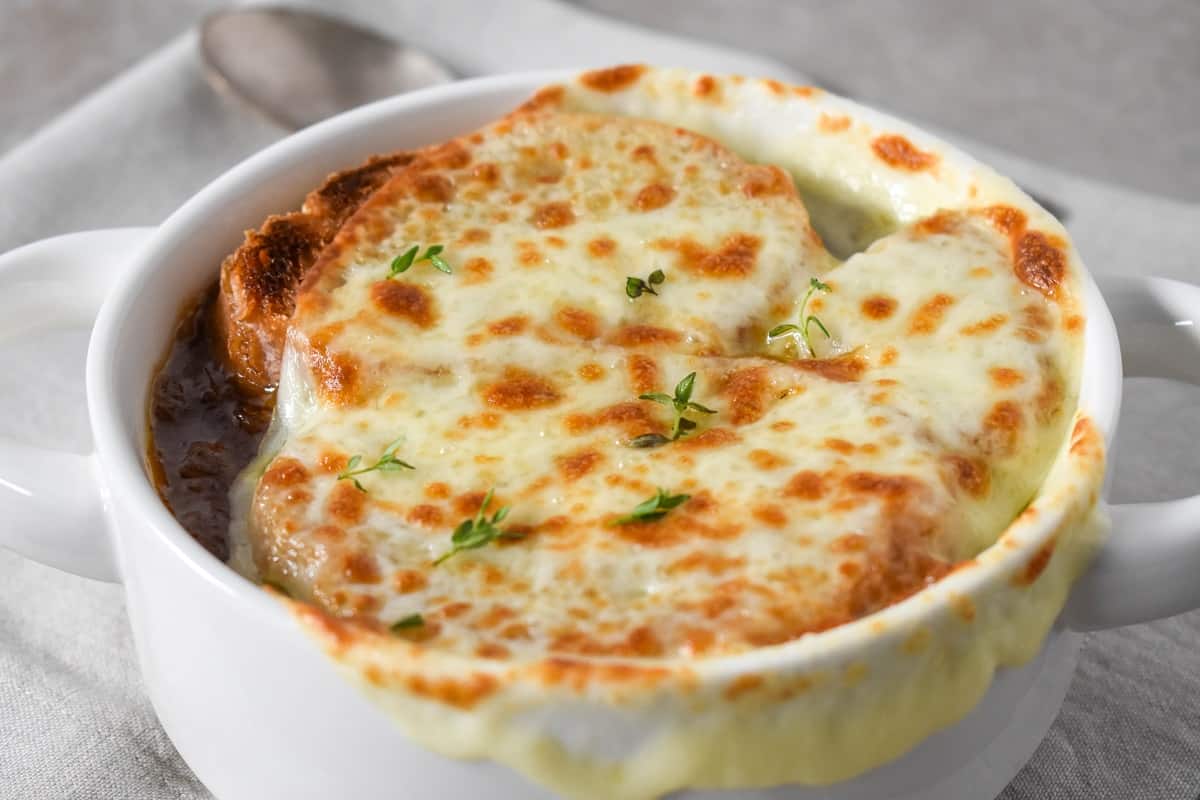 A close-up image of the soup with the cheese melted on top and a little down the sides of a white bowl.