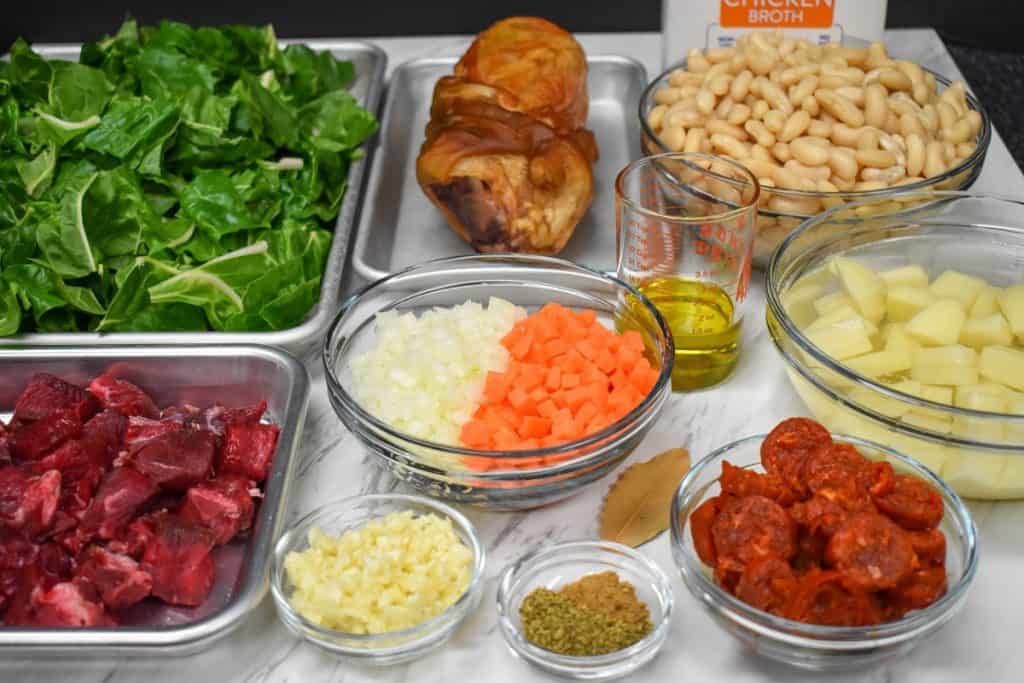 The prepped ingredients for the white bean soup displayed on a white table.