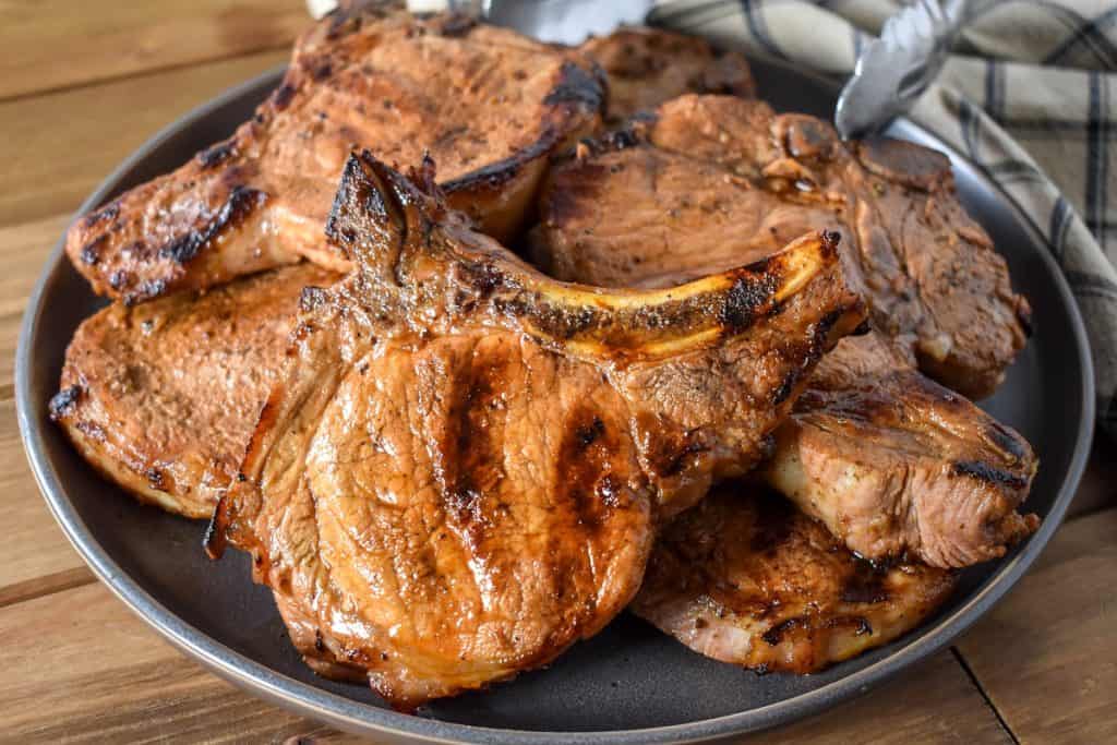 Grilled thick cut, bone-in pork chops served on a large gray plate.