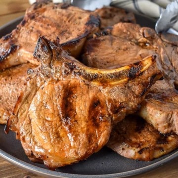 Grilled thick cut, bone-in pork chops served on a large gray plate.