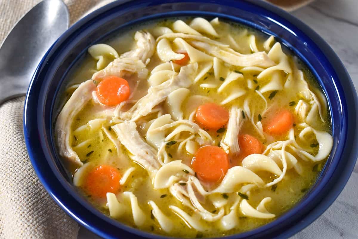 Chicken egg noodle soup served in a blue bowl.