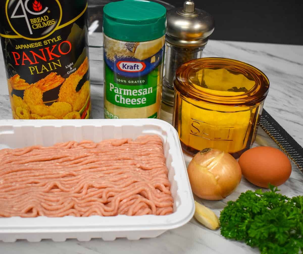 The ingredients for chicken meatballs displayed on a white table.
