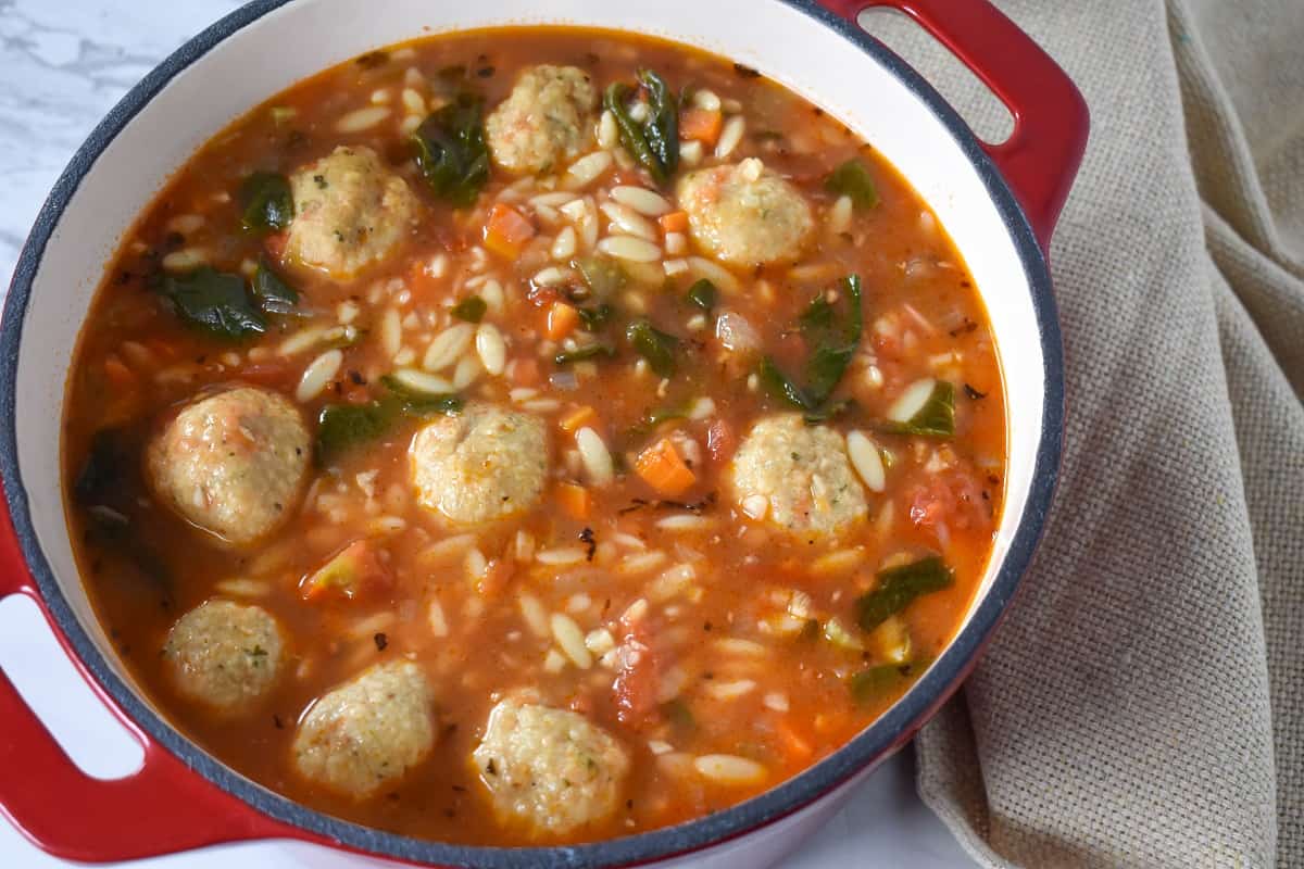 Chicken meatball soup in a red dutch oven.