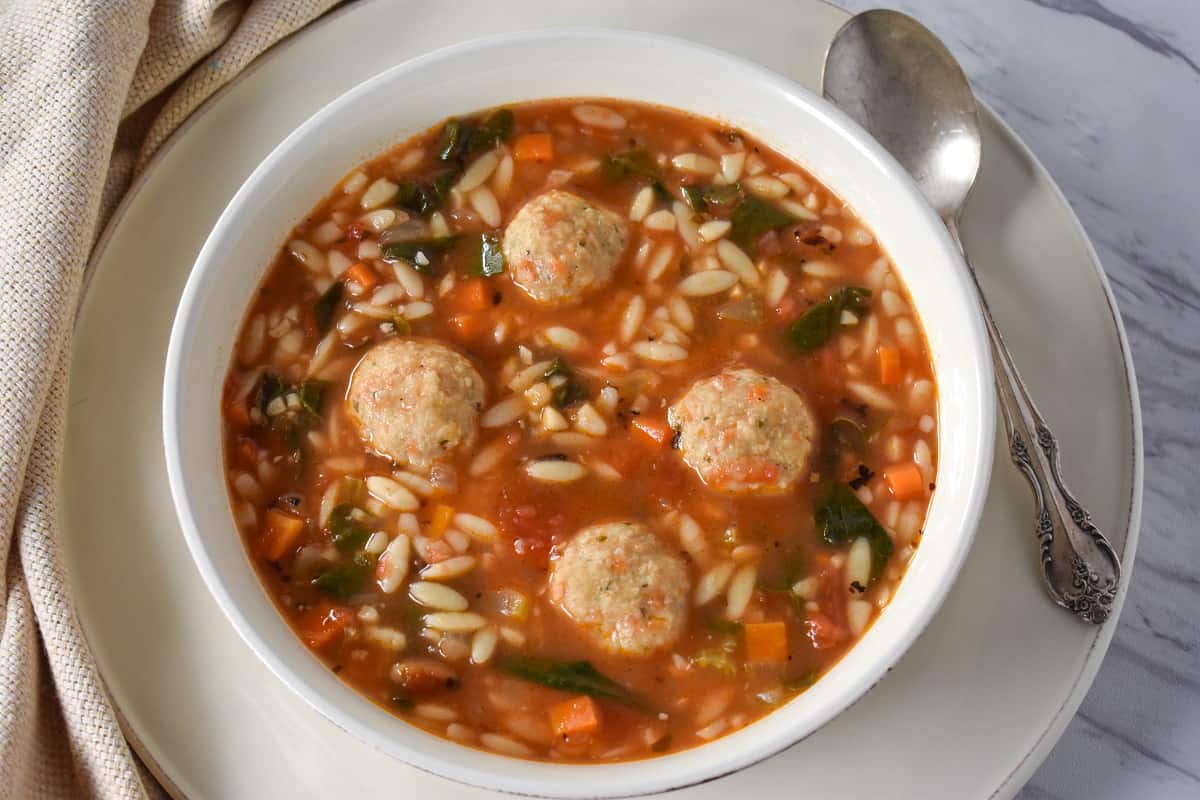 Chicken meatball soup served in a large white bowl.