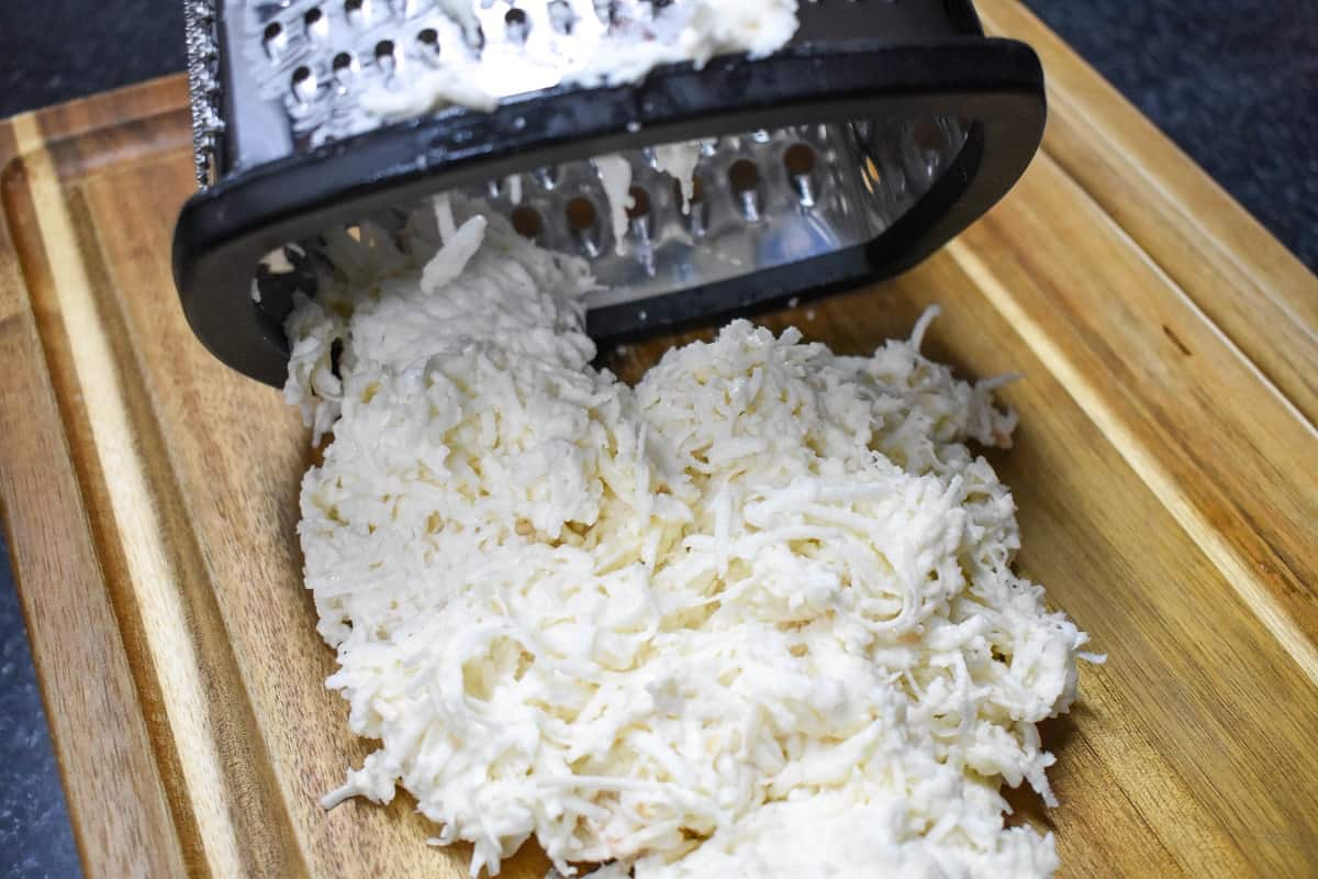 Grated malanga on a wood cutting board.