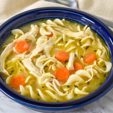 Chicken egg noodle soup served in a blue bowl.