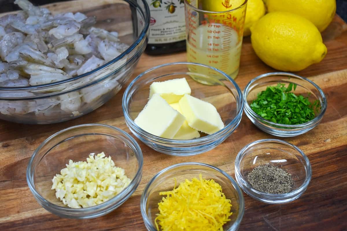 The ingredients for the lemon pepper shrimp displayed on a wood cutting board.