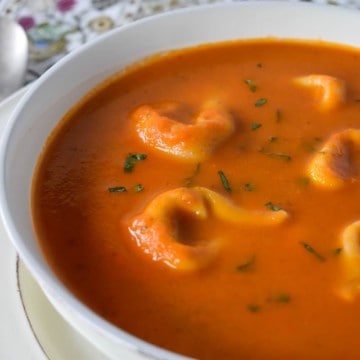 Tortellini tomato soup served in a large white bowl.