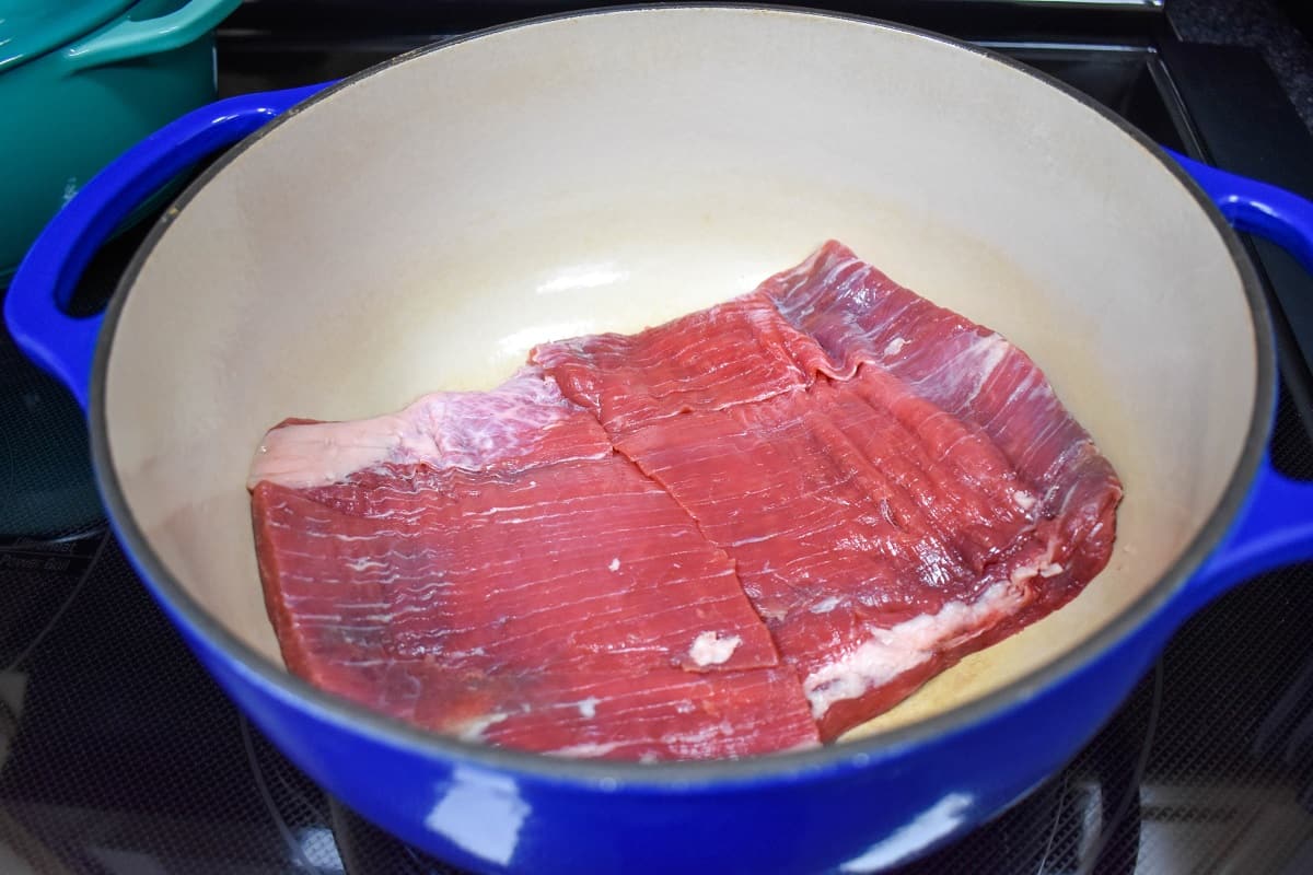 Flank steak in a blue and white pot.