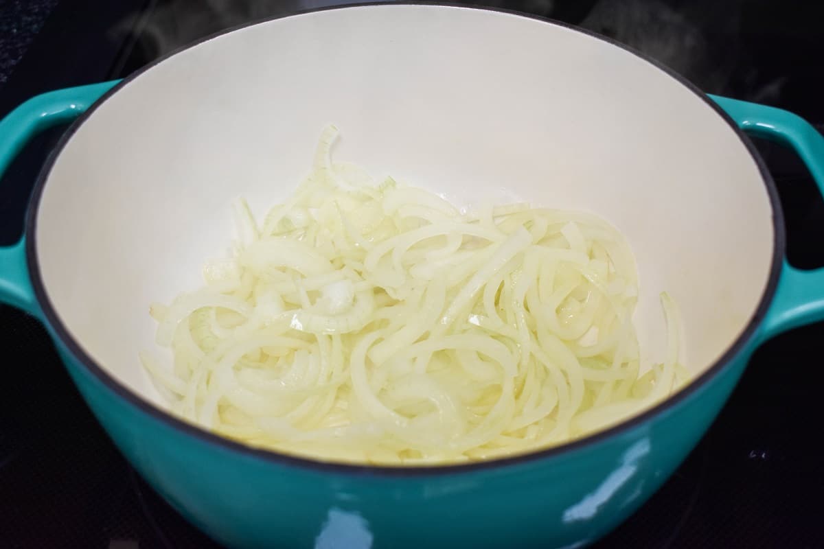 Sliced onions in a light blue and white pot.