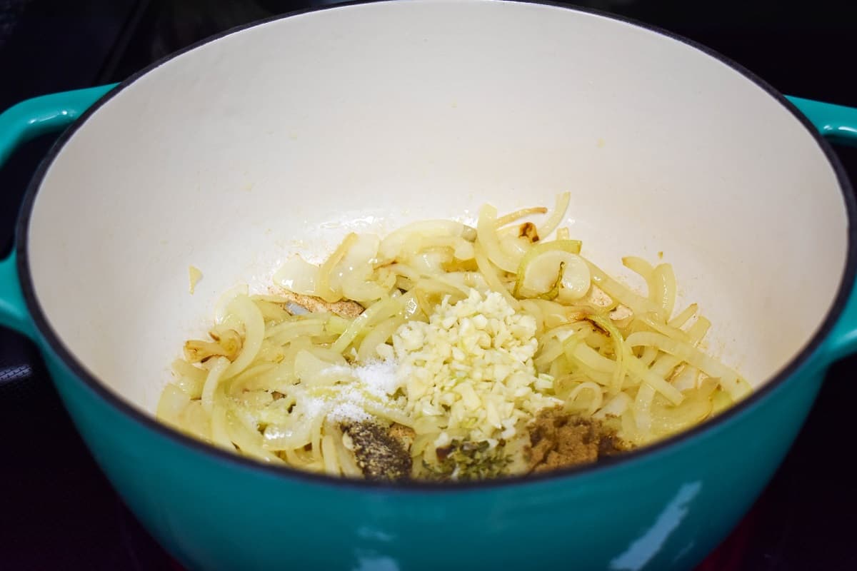 Cooked onions, garlic, and spices in a light blue and white pot.