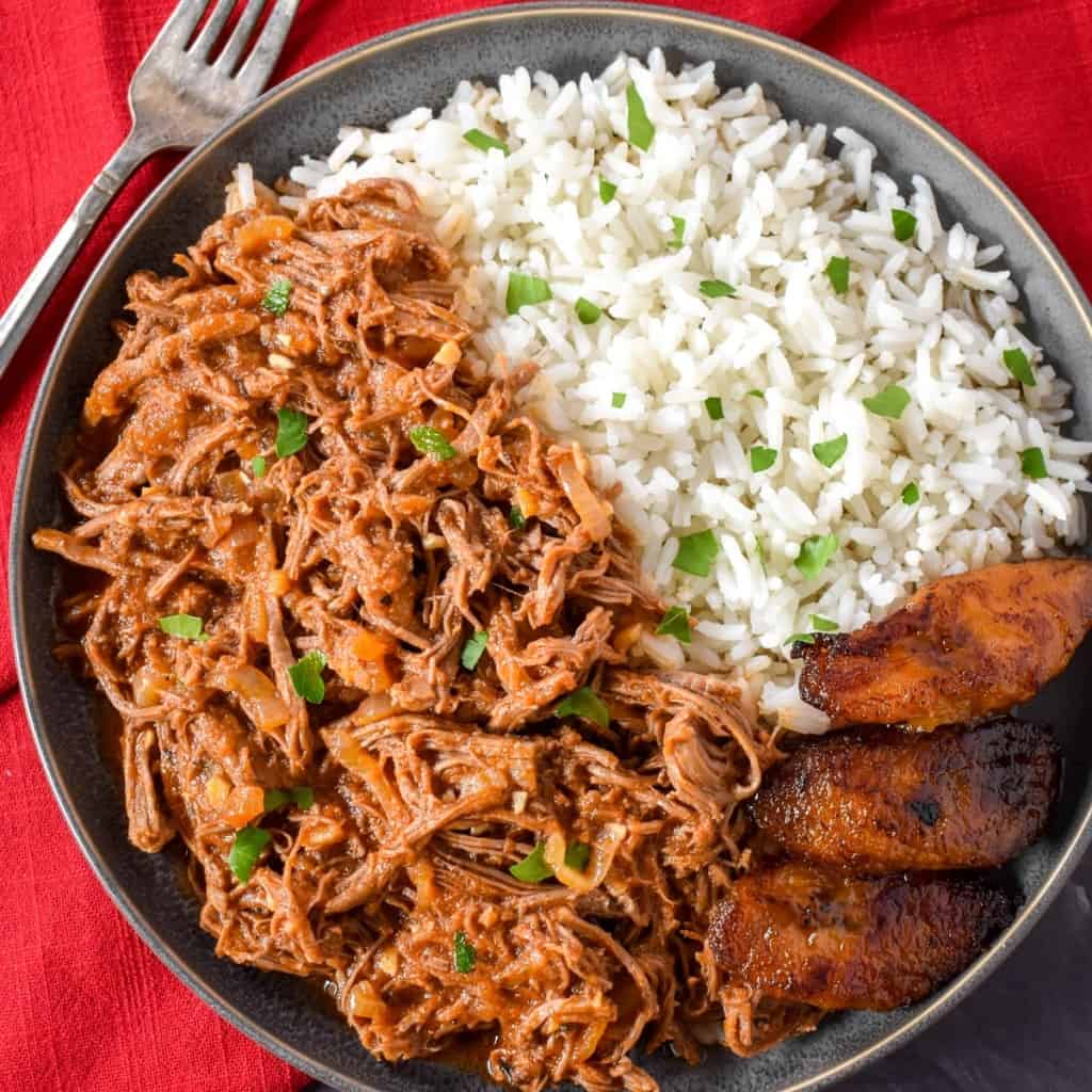 The finished ropa vieja served with white rice and fried sweet plantains on the side.