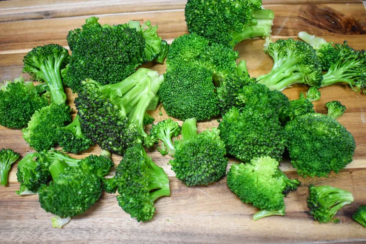Cooked broccoli florets on a wood cutting board.