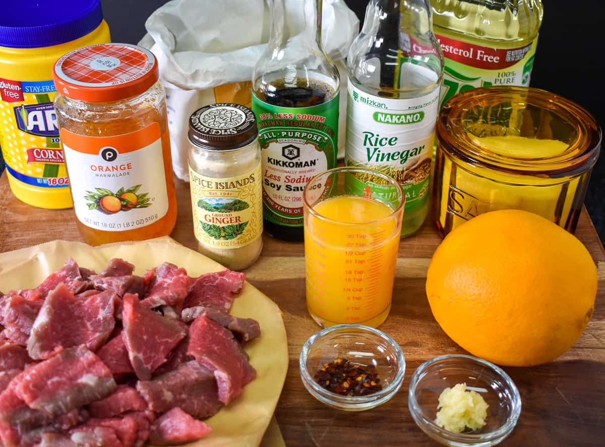 The ingredients for the orange beef arranged on a wood cutting board.