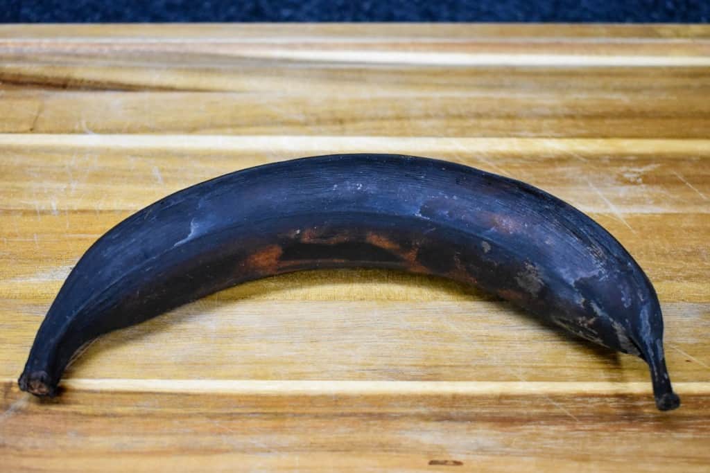 A ripe plantain on a wood cutting board.