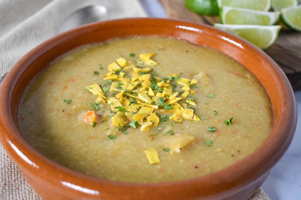 Sopa de platano served in a terracotta bowl with lime wedges in the background.