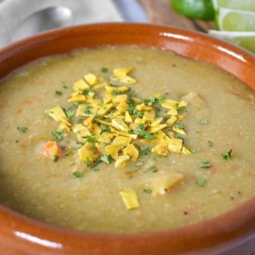 Sopa de platano served in a terracotta bowl with lime wedges in the background.