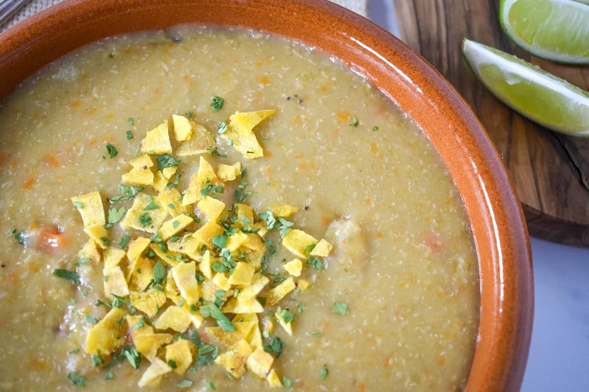 Sopa de plátano adornada con chips de plátano triturados y cilantro picado.