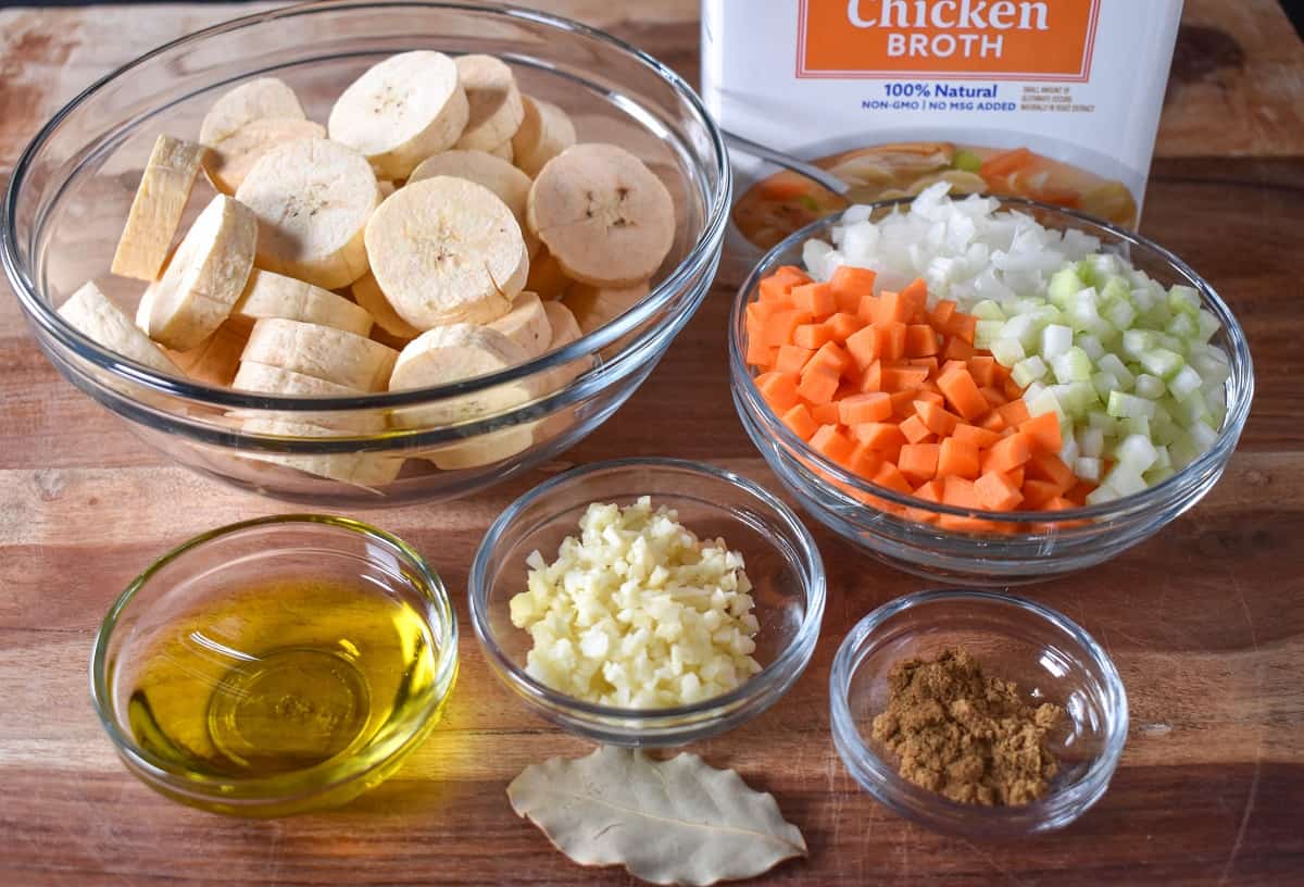 Los ingredientes preparados para la sopa se muestran en tazones de vidrio sobre una tabla de cortar de madera.